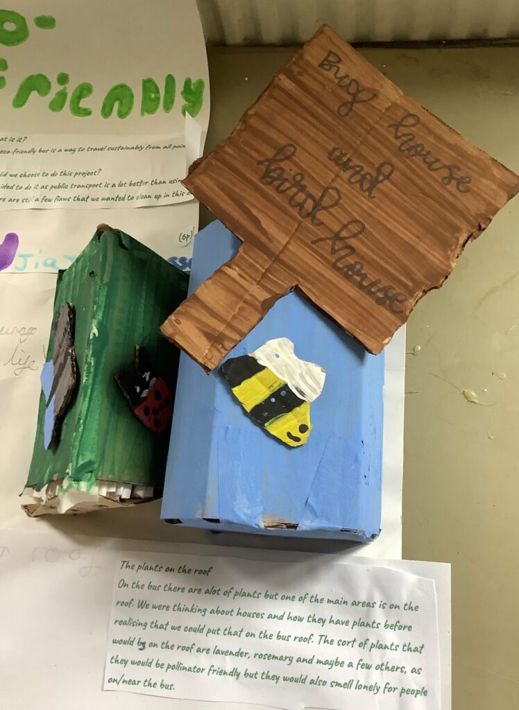 Bug house and bird house Part of the eco-friendly bus display, this model created from recycled card has two built structures. A sign explains that they are a bug house and a bird house. A blue house is decorated with a bee and a green house is decorated with a butterfly and ladybird.